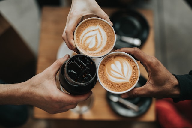 three hands holding three cups of coffee