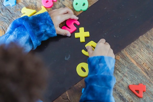 ethnic boy solving mathematical calculation example made of toy numbers and counting numbers