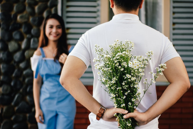 a guy holding flowers surprise present