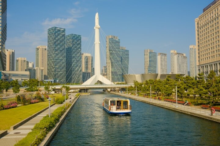 ferry-traveling-down-a-river-next-to-tall-buildings-in-incheon-korea